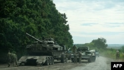 This handout photograph taken Sept. 9, 2022 and released by the press-service of the Commander-in-Chief of the Ukrainian Armed Forces on Sept. 11, shows Ukrainian soldiers loading an abandoned Russian military vehicle on a trailer during the Ukrainian arm