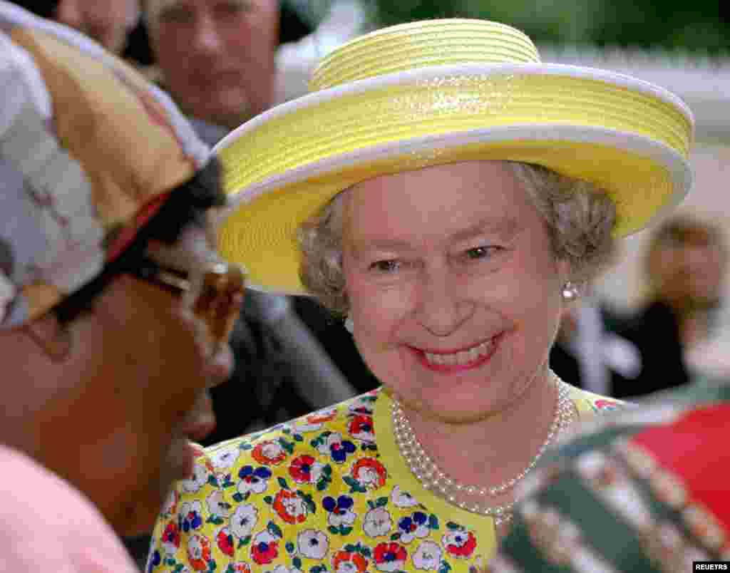 Britain's Queen Elizabeth II chats with an auid in the Natal Society for the Blind in Umbilo near Durban, March 25, 1995. Queen Elizabeth is on the last day of a six day visit to South Africa