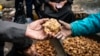 A customer buys a desert truffle from a merchant in a market in Syria's rebel-held northern city of Raqqa on March 14, 2023.