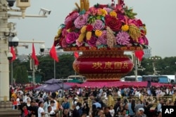 Pengunjung berkumpul di dekat keranjang bunga raksasa yang dipajang di Lapangan Tiananmen yang ramai untuk merayakan ulang tahun ke-74 berdirinya Republik Rakyat China, di Beijing, Kamis, 28 September 2023. (AP/Andy Wong)