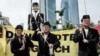 Peserta yang mengenakan masker wajah tiga calon presiden Anies Baswedan, Prabowo Subianto, dan Ganjar Pranowo berjalan di depan boneka raksasa bergambar Pinokio saat demonstrasi di Jakarta, 7 Februari 2024. (Foto : AFP/Yasuyoshi CHIBA)