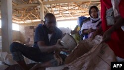 Mfanyakazi wa Shirika la Mpango wa Chakula Duniani (WFP) alisambaza chakula kwa wanawake wa Somalia Decemba19, 2017. Picha na Zacharias ABUBEKER / AFP