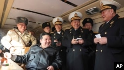 김정은(왼쪽 앉은 이) 북한 국무위원장이 14일 신형 지상 대 해상 미사일 '바다수리-6'형 검수 사격시험을 지도하고 있다며 조선중앙통신이 공개한 사진.