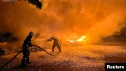 Firefighters extinguish burning trucks damaged during a Russian drone attack at a port on Danube river in Odesa region, Ukraine, Sept. 26, 2023. (State Emergency Service of Ukraine, via Reuters)