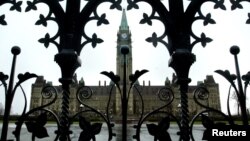 FILE - The Canadian Parliament building is framed through a gate on Parliament Hill in Ottawa, Ontario.