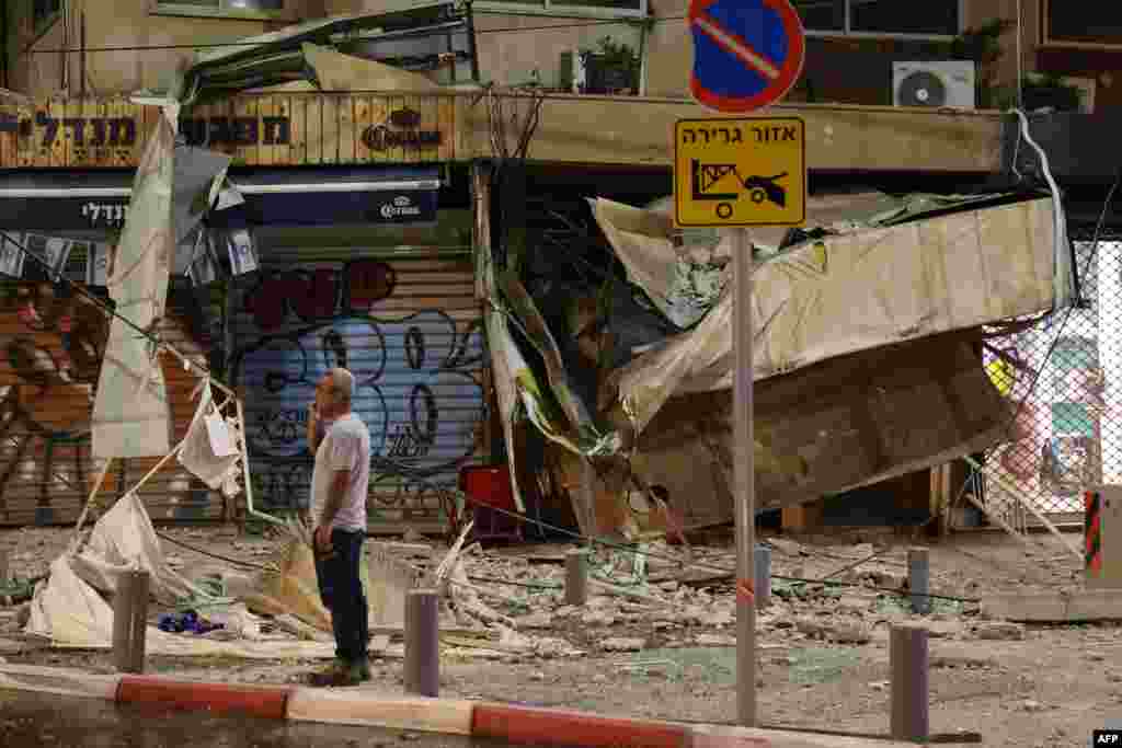 A man stands in front of a damaged shop in Tel Aviv, after it was hit by a rocket fired by Palestinian militants from the Gaza Strip on Oct. 7, 2023. 