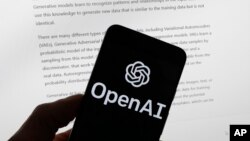 FILE - The OpenAI logo is seen on a mobile phone in front of a computer screen displaying output from ChatGPT, March 21, 2023, in Boston. 