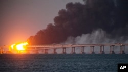 FILE - Flame and smoke rise from the Crimean Bridge connecting the Russian mainland and the Crimean Peninsula over the Kerch Strait, in Kerch, Crimea, Oct. 8, 2022.