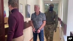 In this handout photo taken from video released by Lefortovo District Court, Robert Shonov walks to the court room 