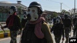 FILE - Security personnel move towards Pakistan Tehreek-e-Insaf (PTI) party activists and supporters of former Pakistan's Prime Minister Imran Khan protesting against the arrest of their leader, in Peshawar on May 10, 2023.
