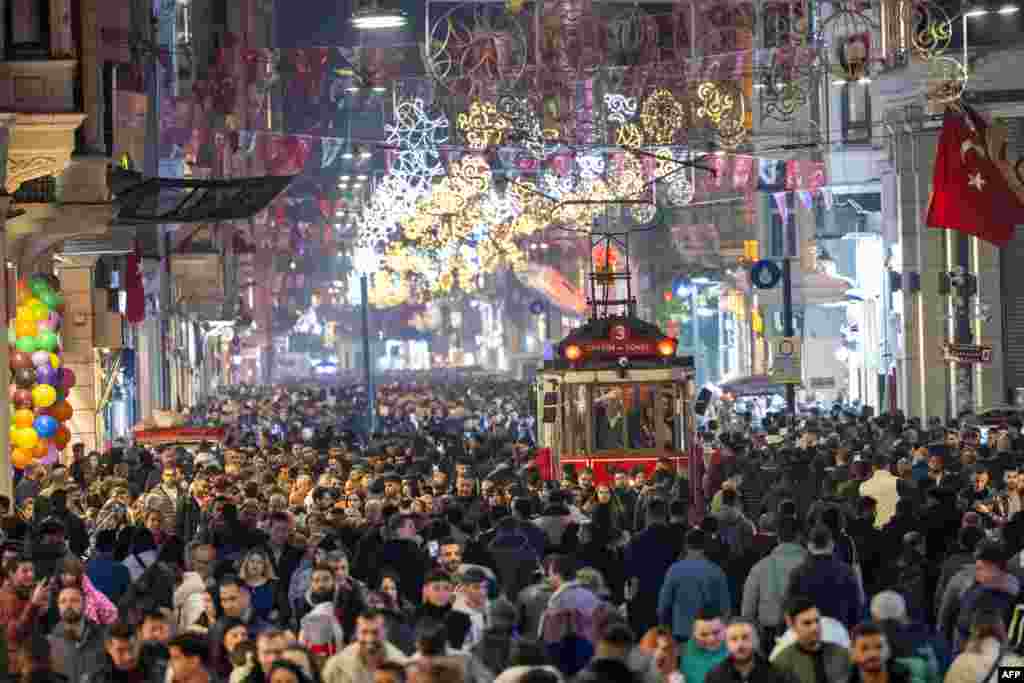 Ljudi prolaze pored istorijskog tramvaja pod svjetlosnim ukrasima u ulici Istiklal tokom priprema za proslavu Nove 2024. godine u Istanbulu, Turska, 31. decembra 2023.