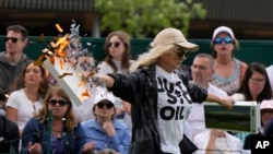 FILE - A Just Stop Oil protester runs onto Court 18 and releases confetti and jigsaw puzzle pieces on day three of the Wimbledon tennis championships in London, Britain, July 5, 2023.