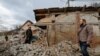 Men stand near buildings damaged in recent shelling in the course of Russia-Ukraine conflict in Donetsk, Russian-controlled, Ukraine, March 12, 2023. 