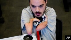 FILE - Martin Shane uses a Sony Access controller, left, to play a video game at Sony Interactive Entertainment headquarters Sept. 28, 2023, in San Mateo, Calif. 