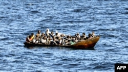 Migrants of African origin are crammed on board a small boat as Tunisian coast guards prepare to transfer them onto their vessel, at sea between Tunisia and Italy, Aug. 10, 2023.
