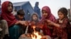 Anak-anak pengungsi Afghanistan menghangatkan diri di api unggun di sebuah kamp dekat perbatasan Pakistan di Torkham, Afghanistan, setelah mereka dideportasi dari Pakistan.