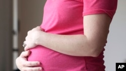 FILE - A pregnant woman poses for a photo in Dallas, Texas, May 18, 2023. The fertility rate in the U.S. dropped in 2023 after a slight two-year rebound following the COVID-19 pandemic, according to a report released Thursday by the Centers for Disease Control and Prevention.   