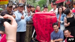 People pose for photographs with a sky lantern with a message of peace written on it at the Shihfeng train station in New Taipei City on April 9, 2023.
