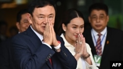 Paetongtarn Shinawatra (kanan) mendampingi ayahnya, mantan Perdana Menteri Thaksin Shinawatra, setibanya di Bandara Don Mueang, Bangkok, Thailand, 22 Agustus 2023. Shinawatra kembali ke negaranya setelah 15 tahun dalam pengasingan. (Foto: Lilian Suwanrumpha/AFP)