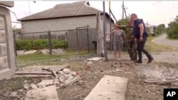 Cette image tirée d'une vidéo montre des personnes montrant un bâtiment endommagé dans la région de Belgorod, en Russie, le 22 mai 2023.