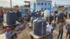 Palestinians queue to collect drinking water from a water treatment station in the central Gaza Strip to distribute to displaced people at shelters, in Deir al Balah, Gaza Strip, Oct. 27, 2023.