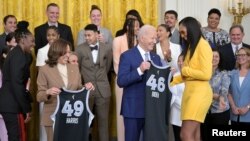 U.S. President Joe Biden is presented with a team jersey by Las Vegas Aces star A'ja Wilson while Vice President Kamala Harris is presented with a jersey by Chelsea Gray during a celebration of the 2023 WNBA champions at the White House on May 9, 2024.