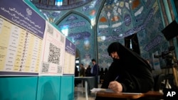 FILE - A woman wears a hijab while filling out her ballot at a polling station in Tehran, Iran, March 1, 2024.