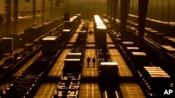 Workers walk among shipping containers at a BNSF intermodal terminal, Jan. 3, 2024, in Edgerton, Kansas. The nation’s employers added a robust 216,000 jobs in December 2023.
