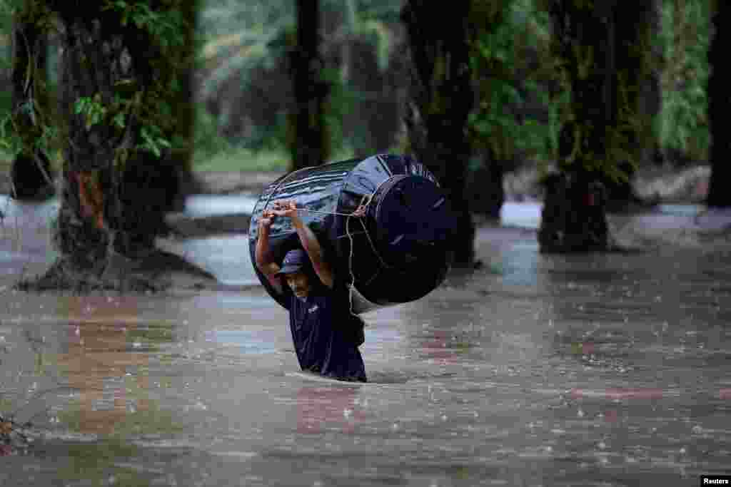 បុរស​ម្នាក់​លី​ធុងទឹក​ទទេរ​មួយ​ឆ្លងកាត់​តំបន់​រង​ទឹកជំនន់ បន្ទាប់​ពី​មាន​ព្យុះត្រូពិច​ Julia ក្នុង​ក្រុង Progreso ប្រទេស​ហុងឌូរ៉ាស កាល​ពី​ថ្ងៃ​ទី ៩ ខែ​តុលា ឆ្នាំ​ ២០២២។