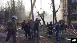 In this photo provided by the Ukrainian Emergency Service, rescuers work at the scene of a building damaged by shelling in Zaporizhzhia, Ukraine, Oct. 9, 2022. 