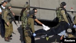 Tentara Israel mengangkat mayat warga Palestina yang ditembak polisi setelah menusuk petugas keamanan dengan pisau di Hebron, Tepi Barat (29/10).
