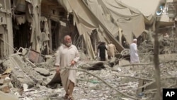 This undated frame grab from video posted online May 29, 2017, by the Aamaq News Agency, a media arm of the Islamic State group, shows people inspecting damage from airstrikes in the northern Syrian city of Raqqa.