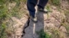 A farmer stands above a deep crack in the dried mud of an earthen embankment in his rice fields on the outskirts of Chongqing, China, Aug. 21, 2022.