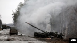 Asap mengepul dari tank Rusia yang dihancurkan oleh pasukan Ukraina di sisi jalan di wilayah Lugansk pada 26 Februari 2022. (Foto: AFP)