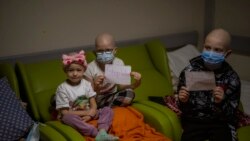 Oncology patients hold up sheets of paper with the words "Stop War" in a basement used as a bomb shelter at the Okhmadet children's hospital in central Kyiv, Ukraine, Monday, Feb. 28, 2022. (AP Photo/Emilio Morenatti)