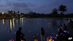 People look at floating handmade boats lit with candles and with the names of Nazi concentration camps, during a ceremony marking the annual Holocaust Remembrance Day in Hayarkon park in Tel Aviv, Israel, April 27, 2022.