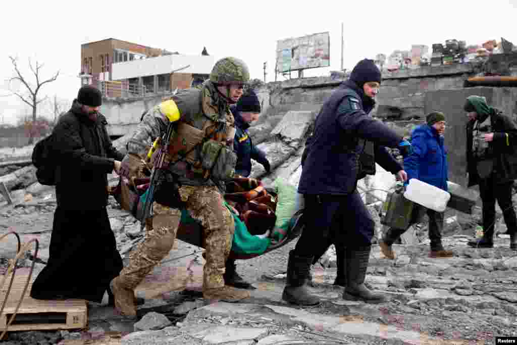 A person is carried as people cross Irpin River as Russia&#39;s invasion on Ukraine continues, in Irpin outside Kyiv, March 9, 2022.