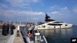 Polisi Keuangan Italia berdiri di samping kapal pesiar "Lady M", milik oligarki Rusia Alexei Mordashov, berlabuh di pelabuhan Imperia, Italia, Sabtu, 5 Maret 2022. (Foto: AP)