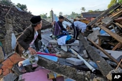Warga mencari barang layak pakai dari rumahnya yang hancur akibat gempa yang menghantam Cianjur, Jawa Barat, Kamis, 24 November 2022. (Foto: AP/Tatan Syuflana)