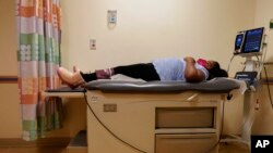 Brooklynn Chiles, 8, lies on an exam room table during a followup visit to Children's National Hospital in Washington, Feb. 11, 2022. 