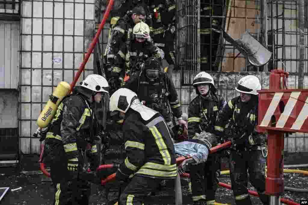 Zjarrfikësit largojnë trupin e një gruaje që vdiq në apartmentin e saj të shkatërruar pas bombardimeve në Kiev, më 15 mars 2022, në sulmet që shkaktuan vdekjen e të paktën dy personave, njoftojnë shërbimet urgjente ukrainase. Një seri shpërthimesh të fuqishme goditën zonat e banimit në Kiev, pak orë para vazhdimit të bisedimeve midis Ukrainës dhe Rusisë.&nbsp;