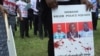FILE - A protester holds a sign picturing human rights attorney Willie Kimani, his client. Josephat Mwenda. and their taxi driver. Joseph Muiruri. allegedly killed by police, at a rally in Nairobi, Kenya, July 4, 2016. (J. Craig/VOA)