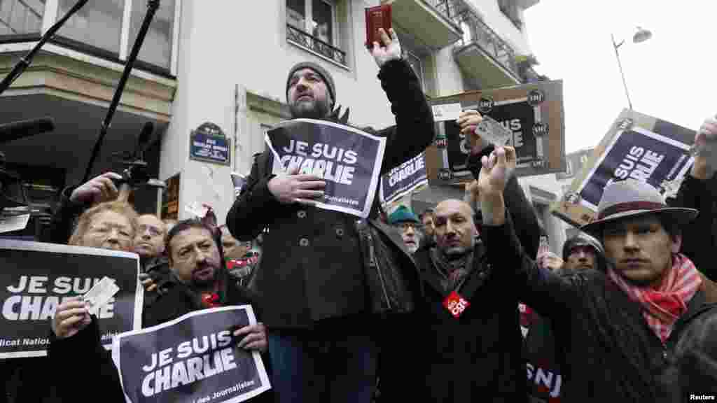 Les journalistes tiennent des pancartes mentionnant &laquo;Je suis Charlie&quot; et leurs cartes de presse pendant une minute de silence devant les bureaux parisiens de journal hebdomadaire satirique Charlie Hebdo à Paris, le 8 janvier 2015