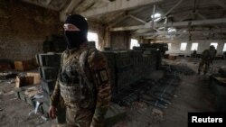 A Ukrainian soldier stands next to cases of ammunition abandoned by retreating Russian forces in the village of Blahodatne, in Ukraine's Kherson region, Nov. 11, 2022.