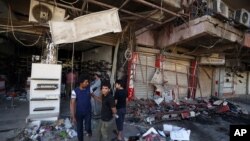 Warga melihat lokasi ledakan bom mobil di Baghdad, Irak (3/5). (AP/Hadi Mizban)