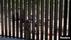 US Customs and Border Protection supervisory agent Carlos Ruiz, left, speaks with a member of the Mexico national guard performing a mirror patrol near Sasabe, Arizona, May 10, 2022.