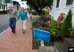Joe Galli u šali pokriva lice prolazeći pored znaka Obama-Biden ispred kuće susjeda u Portsmouthu u New Hampshireu, 5. oktobra 2012.
