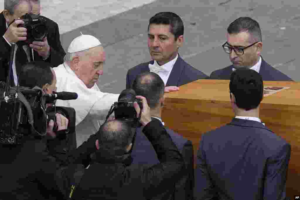 Pope Francis touches the coffin of late Pope Emeritus Benedict before it is carried away after a funeral mass in St. Peter's Square at the Vatican, Jan. 5, 2023.