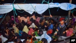 Para pengungsi Rohingya duduk di atas kapal kayu ketika kapal tersebut tiba di pelabuhan Krueng Geukueh, Aceh Utara, pada 30 Desember 2021. (Foto: AP/Rahmat Mirza)