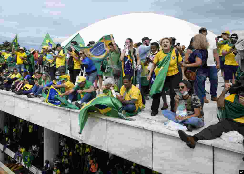 Manifestantes, simpatizantes del expresidente brasileño Jair Bolsonaro, se pararon en el techo del edificio del Congreso Nacional después de que lo asaltaron, en Brasilia, el domingo 8 de enero de 2023. 